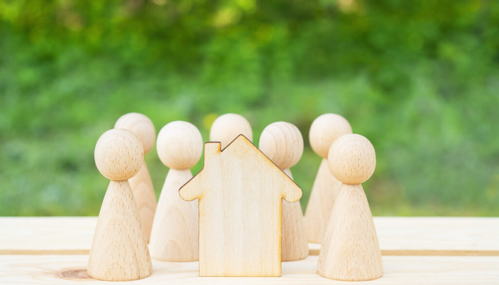 Family concept. Wooden house and many little men on a wooden table. Property division. Copy space
