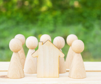 Family concept. Wooden house and many little men on a wooden table. Property division. Copy space