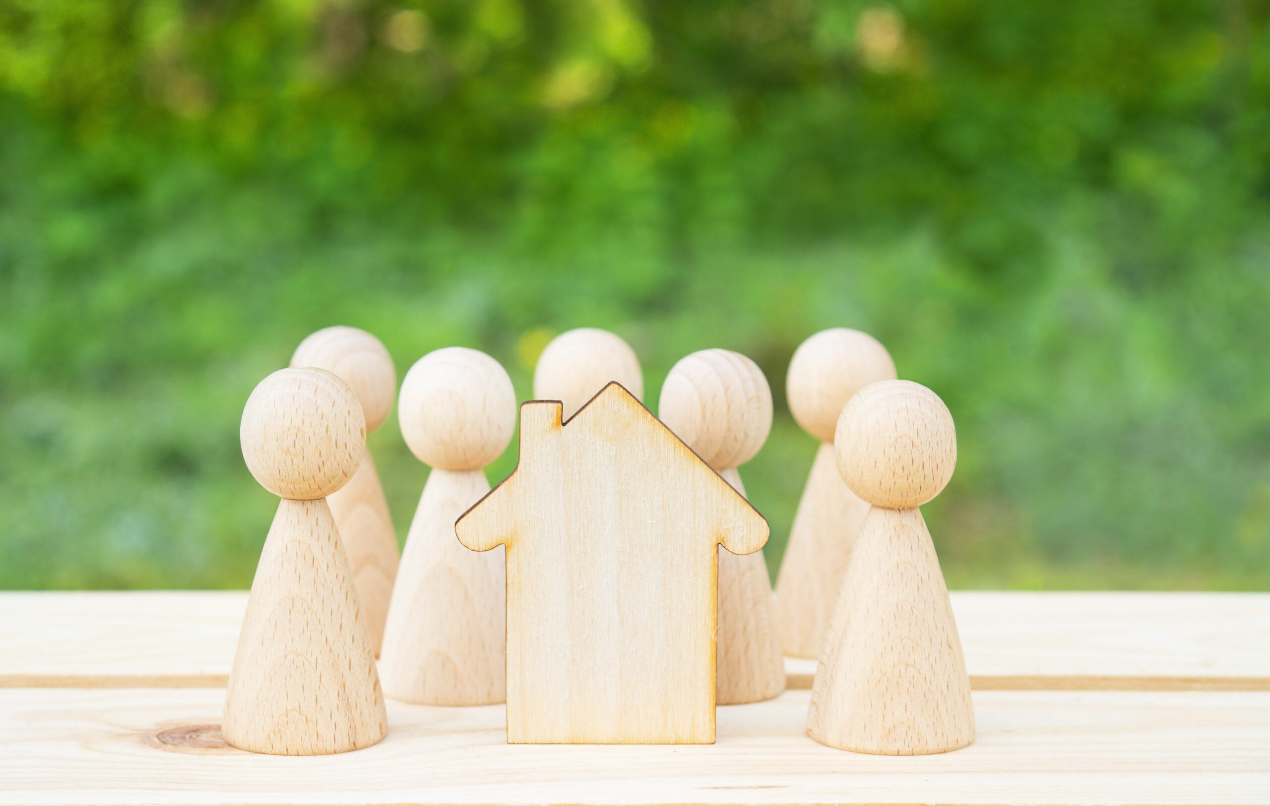 Family concept. Wooden house and many little men on a wooden table. Property division. Copy space Family concept. Wooden house and many little men on a wooden table. Property division. Copy space