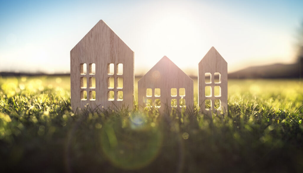 Ecological wood model house in empty field at sunset