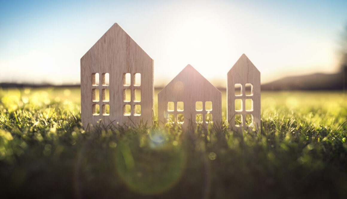 Ecological wood model house in empty field at sunset